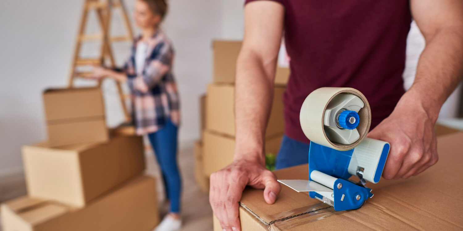 man-with-adhesive-tape-packing-boxes