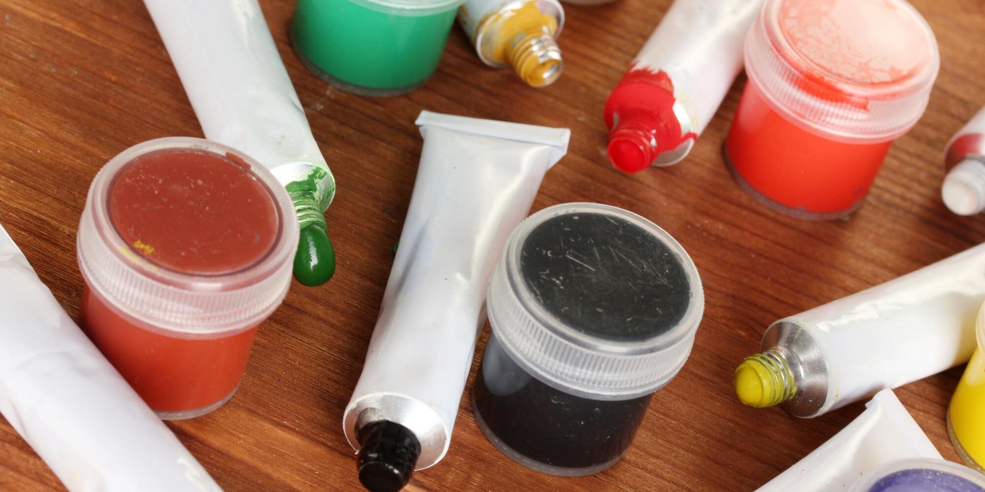 tubes-with-colorful-watercolors-jars-with-gouache-wooden-table-closeup