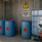 Secure hazardous chemical storage area with blue drums and safety-labeled containers, illustrating safe chemical storage compliance practices in industrial settings.
